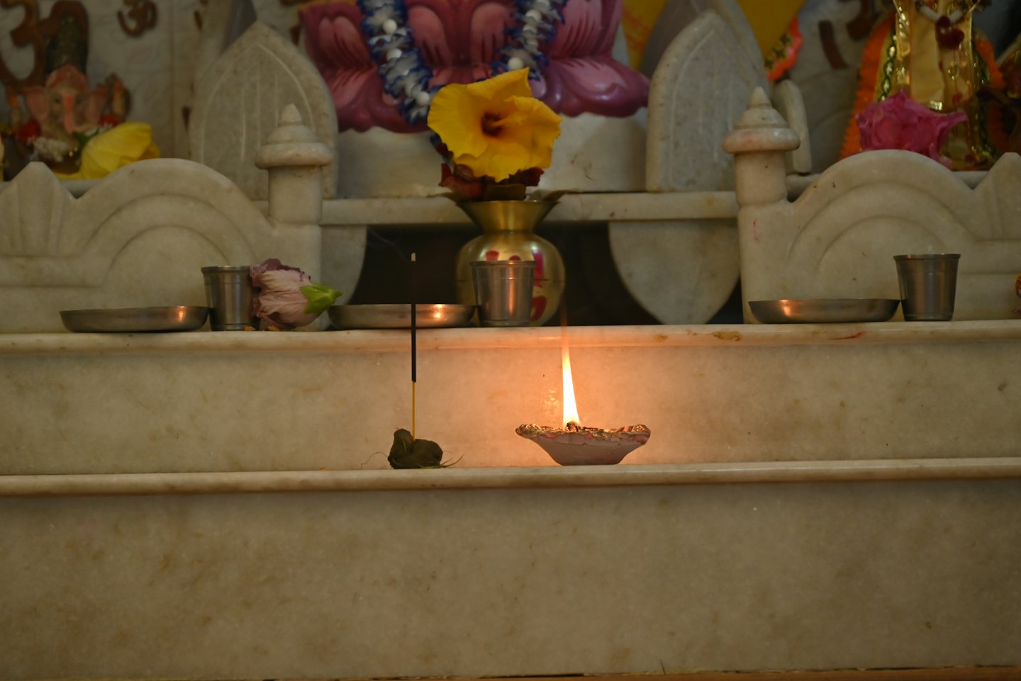 A lit oil lamp and incense on a marble altar.